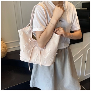 Detail view of pink tote bag with white floral 3D decorations and delicate ribbon bow