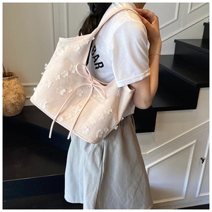 Detail of floral canvas tote bag featuring 3D lace flowers and delicate ribbon tassels