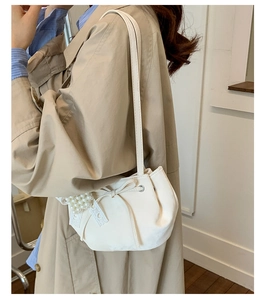 Détail du sac seau crème avec nœud en dentelle et accessoires de perles élégants