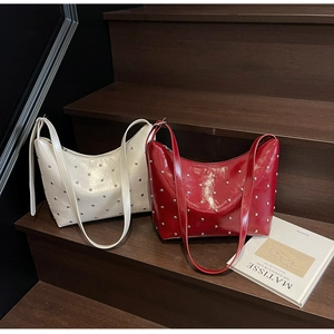 Detailed view of red and beige glossy leather hobo bags with silver metallic studs