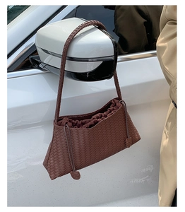Detailed view of dark brown woven texture and drawstring design of a shoulder bag