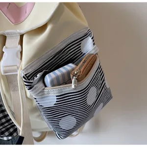 Detail of canvas backpack side pocket with striped zipper and brown card holder