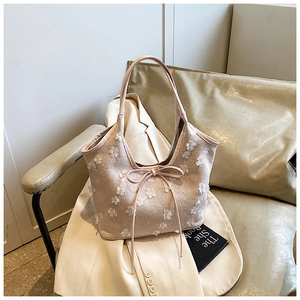 Close-up of 3D floral appliques and bow detail on light beige canvas tote bag