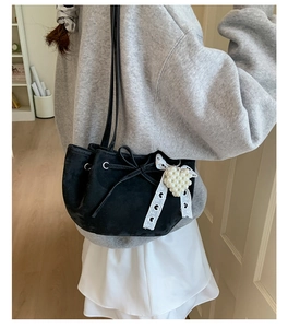 Détail d'un sac noir à cordon avec pendentif cœur en perles et ruban en dentelle