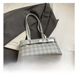 Detailed view of silver grey checkered baguette bag with metal buckle on grey suit background