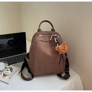 Detail of vintage brown canvas backpack with leather handle and a cute plush bear charm