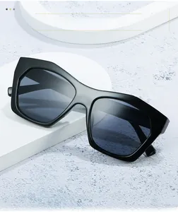 Close-up of black geometric sunglasses on white pedestal with marble background