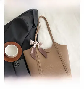 Close-up of brown lychee leather tote bag with leopard print scarf and long shoulder strap
