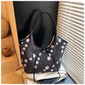 Close-up of a floral canvas tote bag featuring 3D white flower patches and a bow tie