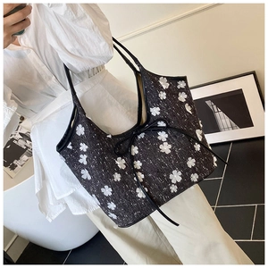 Detail of tweed bucket bag featuring white 3D flowers and black bow tie decoration