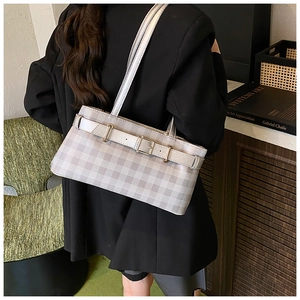 Detail of checkered baguette bag with belt buckle on a model in a black blazer