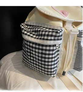Detail of checkered side pocket on beige canvas backpack with secure zipper closure