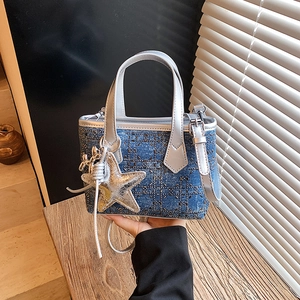 Blue denim bucket bag with silver handles and star charm shown in a handheld view