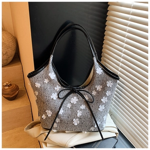 Detail of grey tweed tote bag with 3D white flower accents and black bow ribbon