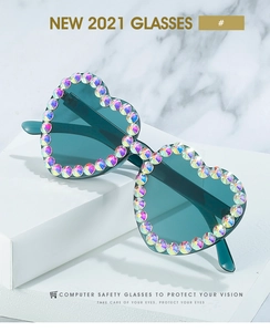 Macro detail of heart-shaped sunglasses with iridescent rhinestones and cyan blue lenses