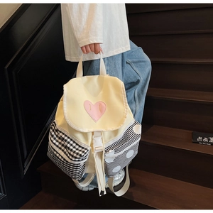 Detail of beige backpack featuring pink heart patch and stylish checkered side pockets