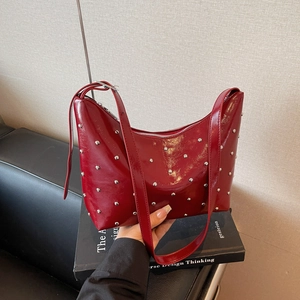 Red patent leather crescent hobo bag with metal rivets and vintage rock style