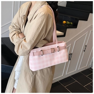Detail of pink plaid baguette bag with leather strap and metal buckle on beige coat
