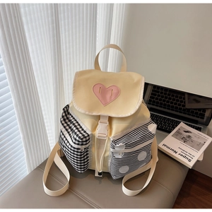 Detail of cute backpack featuring pink heart patch and asymmetric plaid patterned pockets