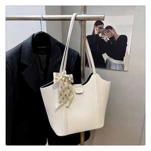 Detail of white lychee leather tote bag featuring elegant floral scarf on the handle