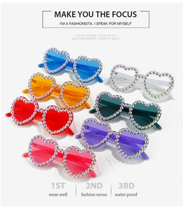 Close-up of heart-shaped sunglasses with sparkling rainbow rhinestones in multiple colors
