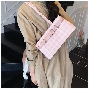 Detail shot of a pink plaid baguette bag with leather strap and silver metal buckle