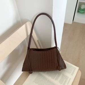 Brown woven leather shoulder bag with top handle displayed on a wooden chair