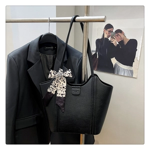 Detail of black pebbled leather tote bag featuring a brand logo and leopard print silk scarf