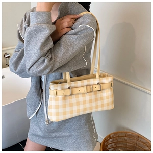 Close-up of a yellow plaid baguette bag with leather strap and metal buckle detail