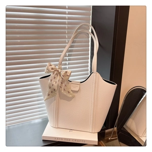 Close-up of white lychee pattern leather tote bag with printed silk scarf handle detail