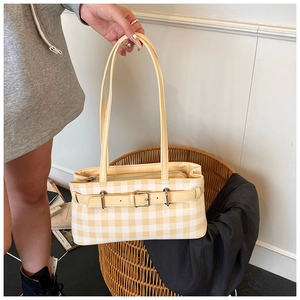 Detail of yellow gingham baguette bag featuring decorative belt buckle and slim shoulder straps