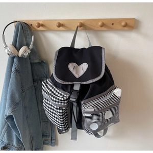 Detail showing mixed pattern side pockets and heart patch on a black canvas backpack