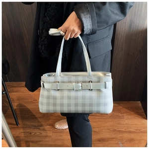 Close-up of grey plaid baguette bag featuring buckle strap detail and sleek leather texture