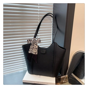 Close-up of black lychee leather tote bag with fashion embossing and leopard ribbon decoration