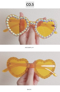 Detail view of yellow heart-shaped sunglasses with sparkling rhinestone embellishments