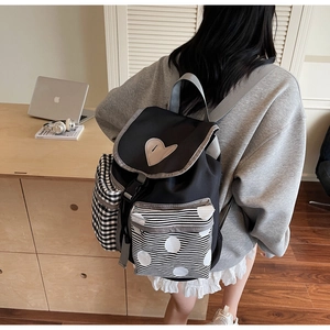 Close-up of contrast patchwork canvas backpack with heart pattern and checkered pockets