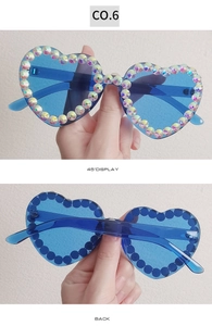 Detail views of heart-shaped sunglasses with blue frame and iridescent rhinestones