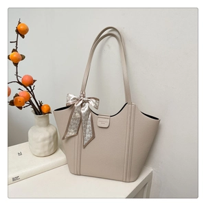 Close-up of beige lychee grain tote bag featuring heart print silk scarf and logo detail