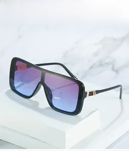 Close-up of oversized square sunglasses with purple gradient lenses and gold metal accents
