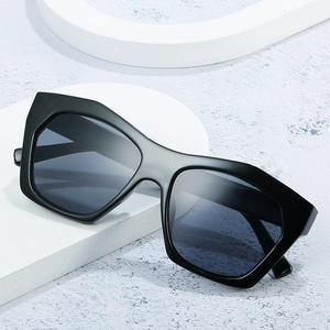 Chic black bold frame geometric sunglasses with dark grey lenses on minimalist stone base