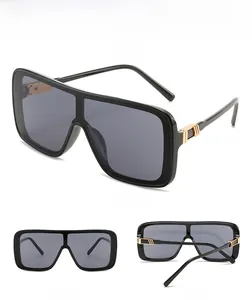 Detail view of large square sunglasses featuring gold metal accents on black temples