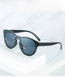 Detail of oversized black sunglasses with silver rivets on white marble background