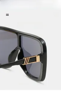 Close-up of golden metal hinges with stripe details on black oversized sunglasses frame