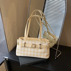 Minimalist yellow plaid baguette bag with leather straps on a book with mirror background