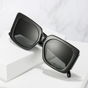 Lunettes de soleil oversize noires à monture rectangulaire sur une surface en marbre