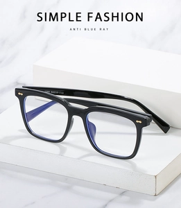 Detail view of TR90 black square frame glasses with gold rivets on marble background