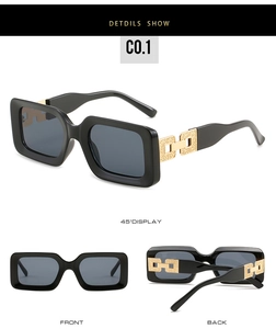 Detail view of square black sunglasses with gold chain link temples and dark lenses