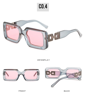 Detail view of pink lens rectangle sunglasses with grey frames and metal chain temples