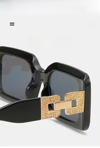 Detailed macro view of black square sunglasses featuring gold hammered metal temples