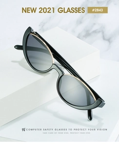 Détail de lunettes œil de chat noires avec bordure en métal doré sur fond de marbre
